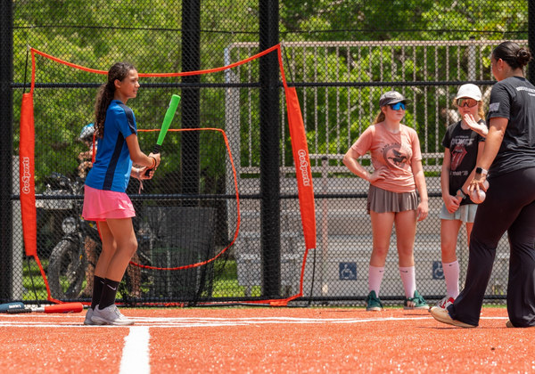 Coach and young softball players at a sports clinic